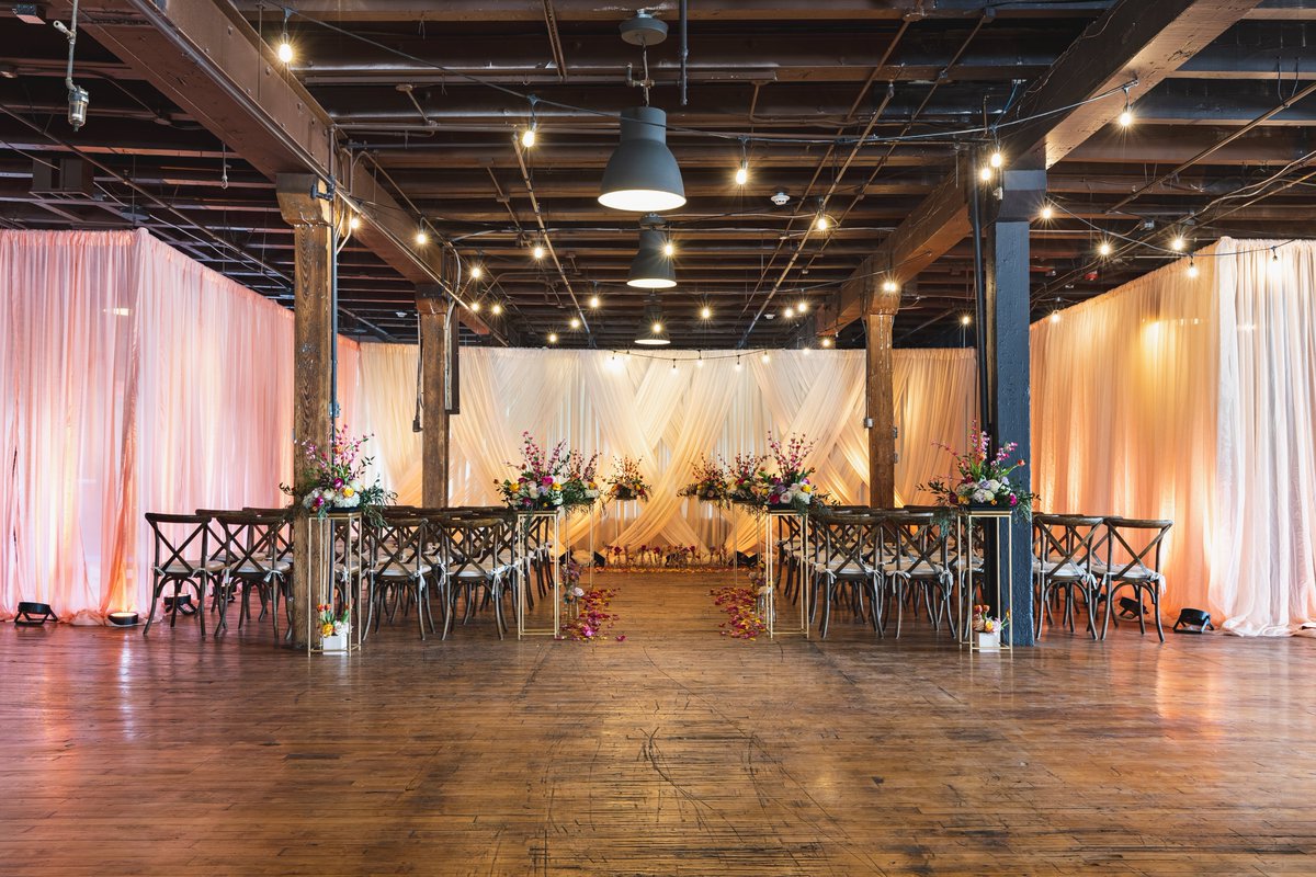 These gorgeous ceremony florals and colorful draping create the perfect backdrop for your special day! 💐