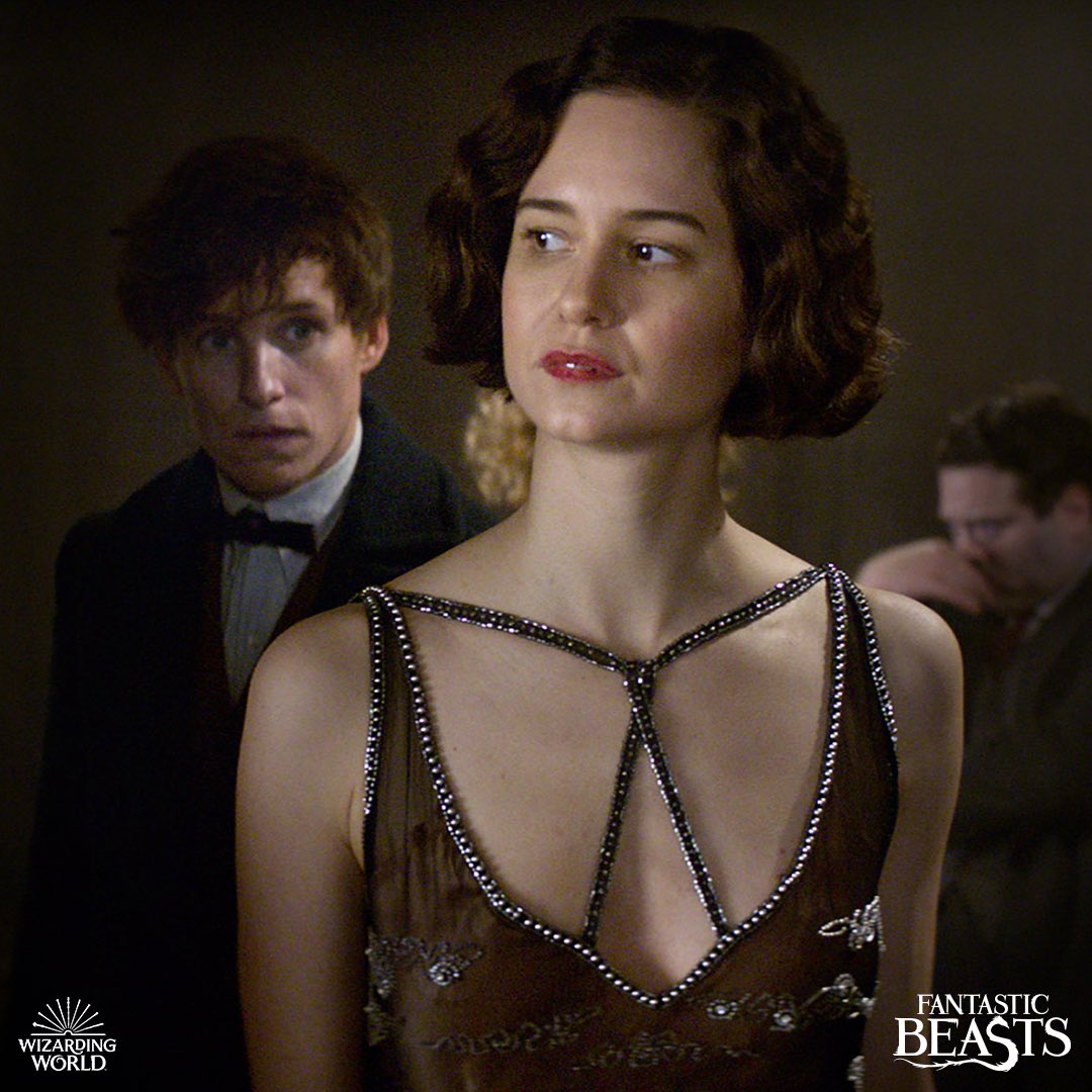 Tina Goldstein looks away, wearing a black embellished gown. Newt Scamander watches her intently.