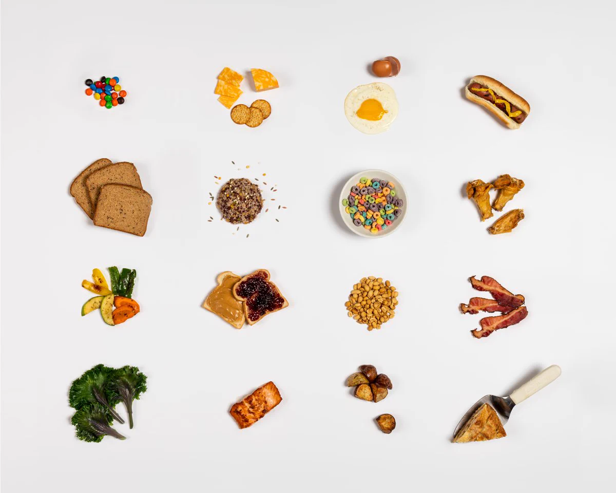 A display of different types of foods including M&Ms, cheese, bread, hotdogs, bacon, salmon, among others.