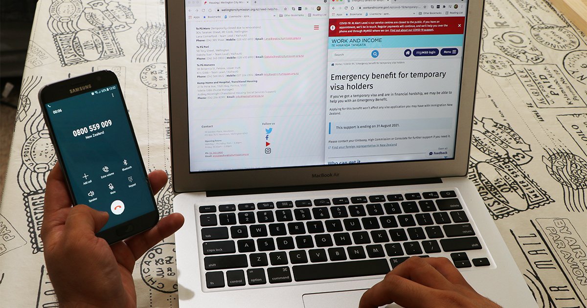 Person working on laptop, viewing websites that offered housing and migrant help information, and holding a mobile phone on a call.