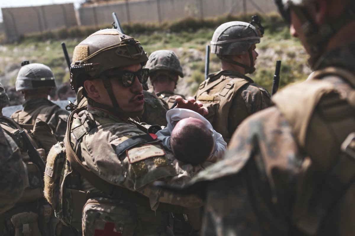U.S. military service members comfort infants at Hamid Karzai International Airport in Kabul, Afghanistan. #HKIA