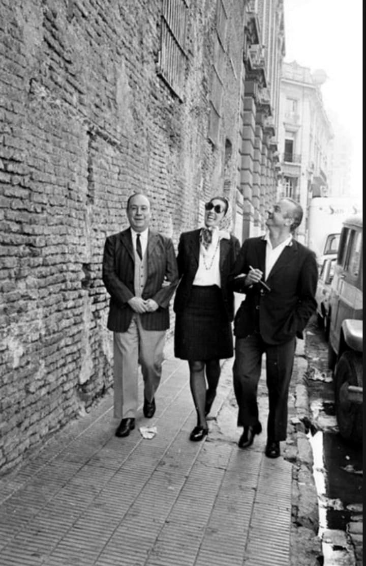 Leopoldo Marechal, Susana Rinaldi y Astor Piazzolla caminando junto a un desconchado paredón de calle Balcarce entre Venezuela y México a fines de los años 60.