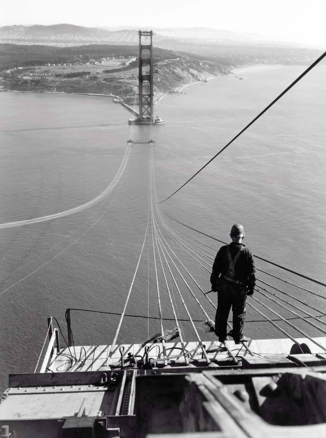 Historybench's tweet image. A man standing on the first cables during the construction of the Golden Gate Bridge, 1935