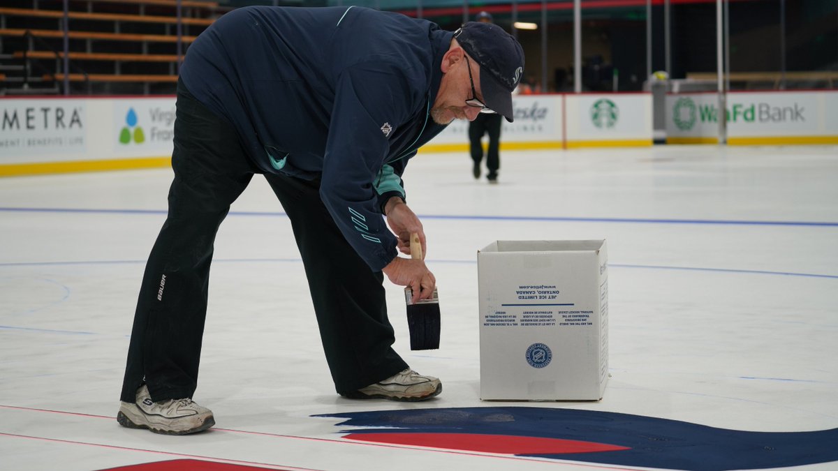 Image of a man painting the Kraken S logo onto the ice.