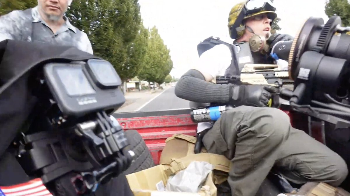 Pic of Randy Ireland in full LARP gear--helmet, goggles, tactical pants, airsoft gun, etc. in the back of a pickup truck with Tiny in Portland leaving the Kmart rally.