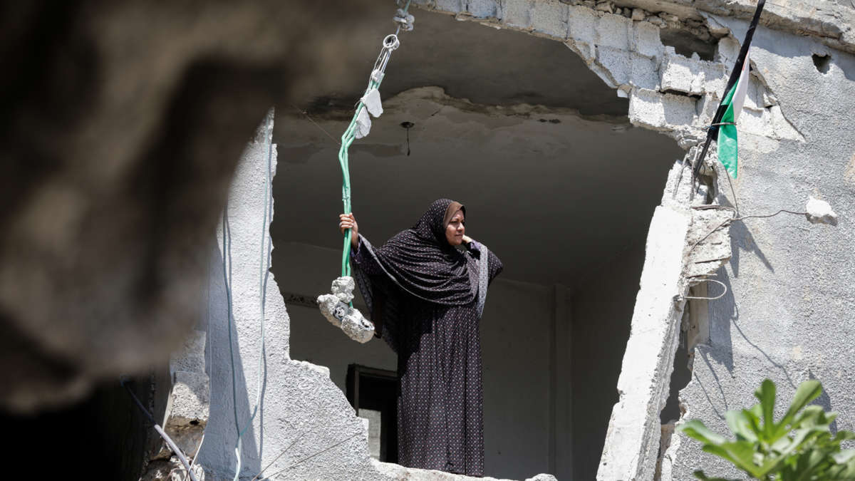 [ID: a Palestinian person stands in a demolished building.]