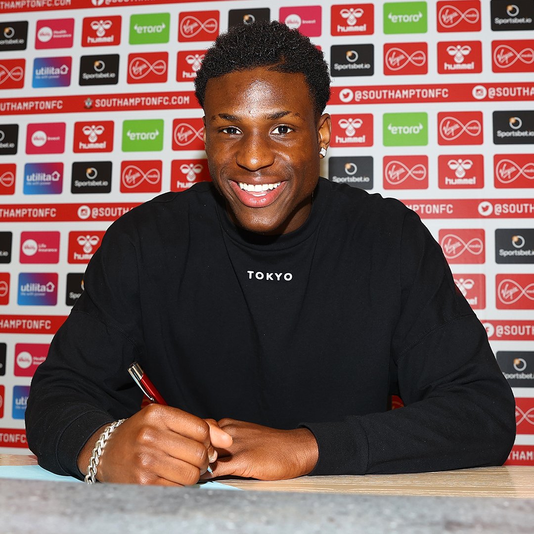 Thierry Small smiles at the camera whilst holding a pen in his hand signing his Southampton contract.