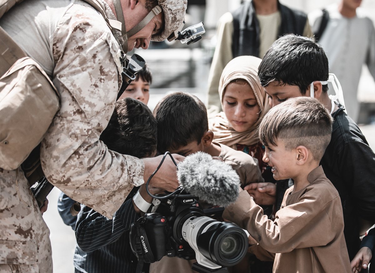 A U.S. Marine assigned to Special Purpose Marine Air-Ground Task Force – Crisis Response – Central Command shows his video camera to children awaiting evacuation at Hamid Karzai International Airport, Afghanistan, Aug. 22, 2021. The U.S. is assisting the Department of State with a Non-Combatant Evacuation Operation (NEO) in Afghanistan. (U.S. Marine Corps photo by Gunnery Sgt. Melissa Marnell)