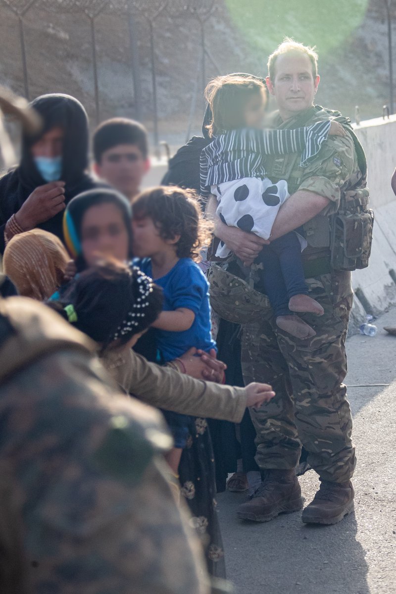 Member of the UK Armed Forces carrying a child.