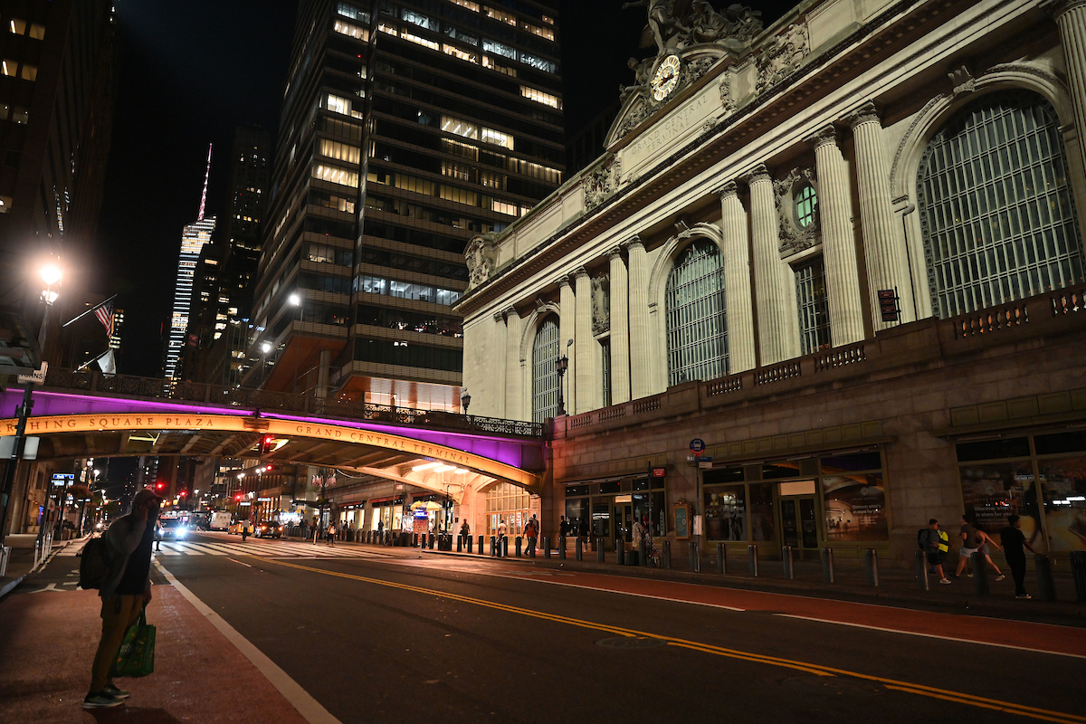 The Pershing Square Plaza Bridge at Grand Central Terminal in NYC lit up in purple and gold in honor of Women's Equality Day