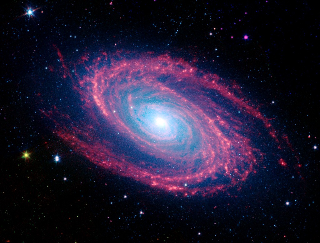 Infrared view of a galaxy. Pink dust clouds circle a bright core. 
