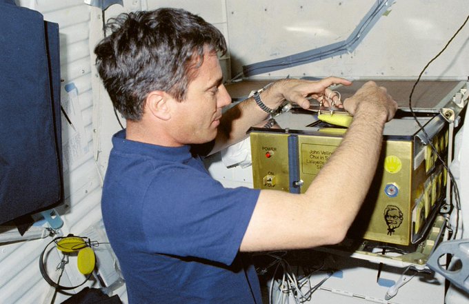 In March 1989, STS-29 Pilot John Blaha checks an incubator for a student experiment called "Chicken Embryo Development in Space" (sponsored by KFC) aboard Space Shuttle Discovery.