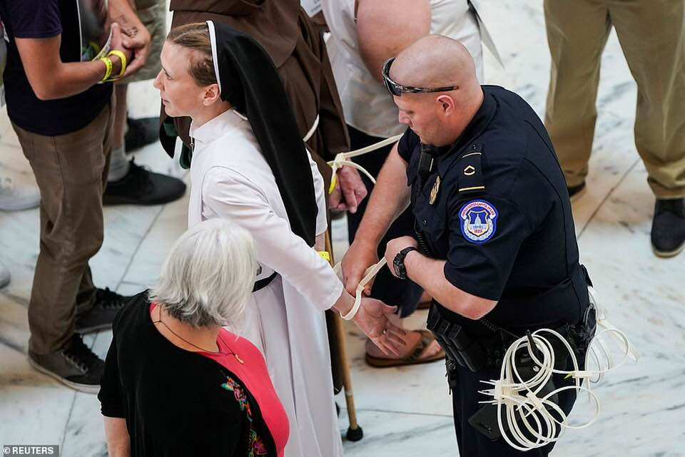 _SJPeace_'s tweet photo. This is America 

Nuns &amp; monks &amp; priests arrested for peacefully protesting against children in cages and the Separation of Children from their parents at the border.

People were wearing the faces of young children who died in these concentration camps around their necks. 💔😭 https://t.co/8f7YvdLx1h