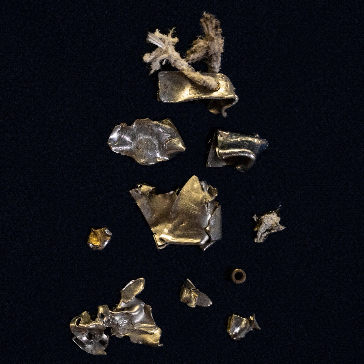 A collection of tiny metal pieces and shards lie on a black background.