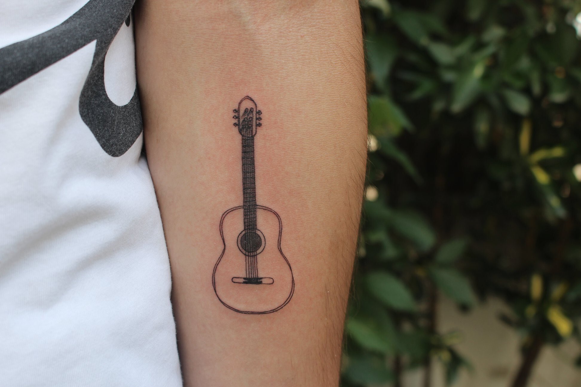 Minimalistic guitar tattoo located on the side boob.