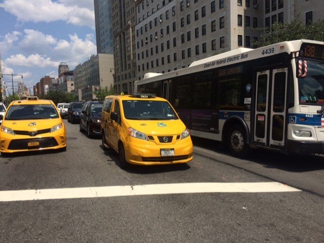 TaxisForAll's tweet image. Two accessible taxis and an accessible bus wait for a light on Adams St. in downtown Brooklyn. On the 29th anniversary of the ADA today, we also salute the power of disability advocates who've sued and won lawsuits that brought these changes to New Yorkers.