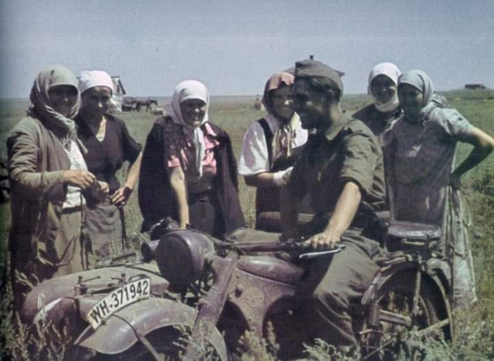 Bir Alman savaş muhabiri BMW R12 model motosikleti üzerinde işgal altındaki Ukraynalı tarım işçileri ile konuşuyor. (1942)