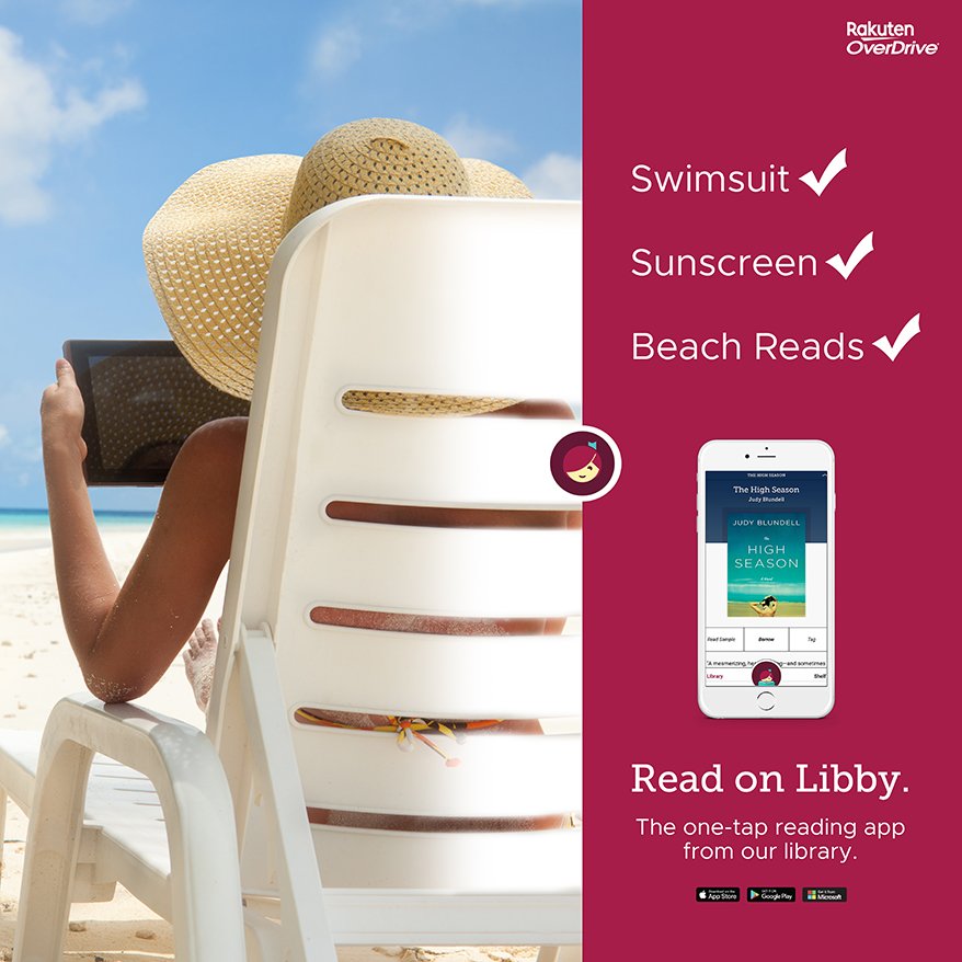 a woman reading a tablet on the beach sitting in a chair wearing a sun hat