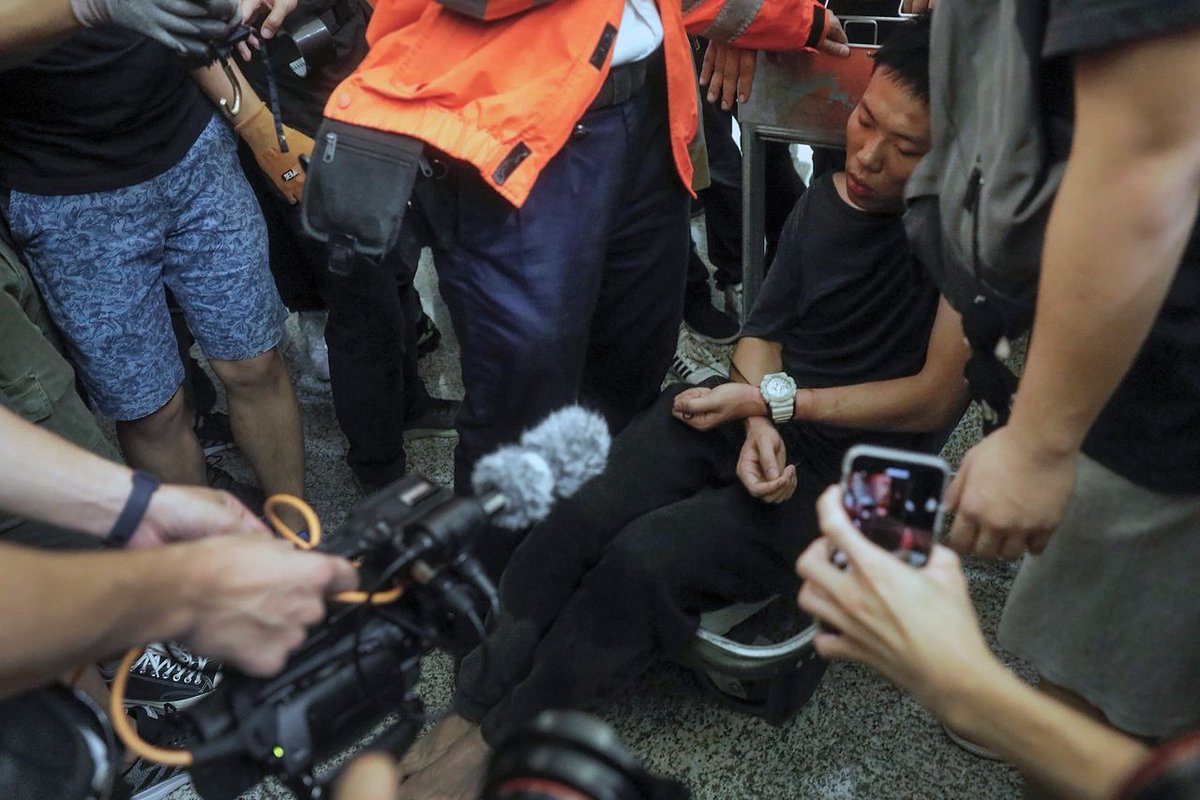 SnitchWatch's tweet image. #HongKongAirport protesters know how to deal with police infiltrators! "Protesters tied the man and shuffled him around the stiflingly hot airport hall for 3 hours, chanting “Bear the consequences.” Witnesses said he was beaten and tied, unconscious, to a luggage trolley." -WSJ