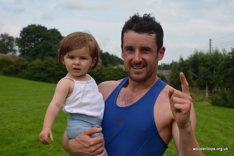 Proud daddy, Harry Coates of Wharfedale Harriers celebrates winning Hellifield Gala senior men's fell race by carrying his daughter across the finish line <a href="/BarlickFellRunn/">Barlick Fell Runners</a> <a href="/Fellrunninbrief/">Fell Running Briefs</a>
