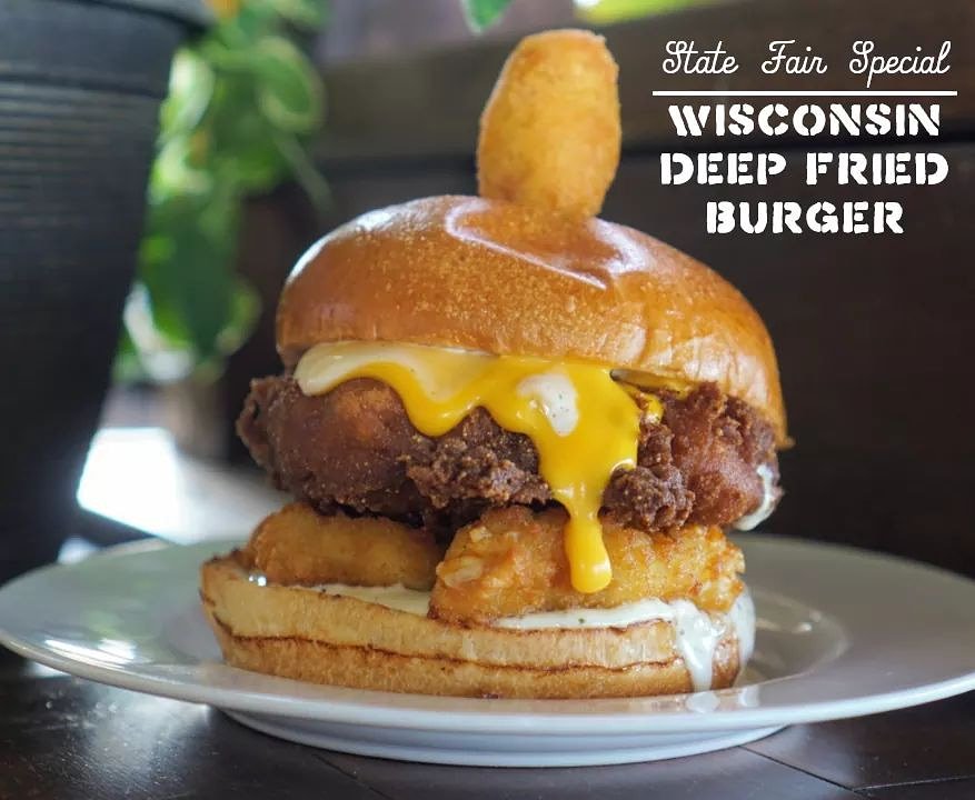 Available only in Oak Creek for a limited time! 

A corn-battered deep fried burger with cheese curds, cheese sauce, and homemade ranch dressing served on your choice of bun topped with a mini corn dog.