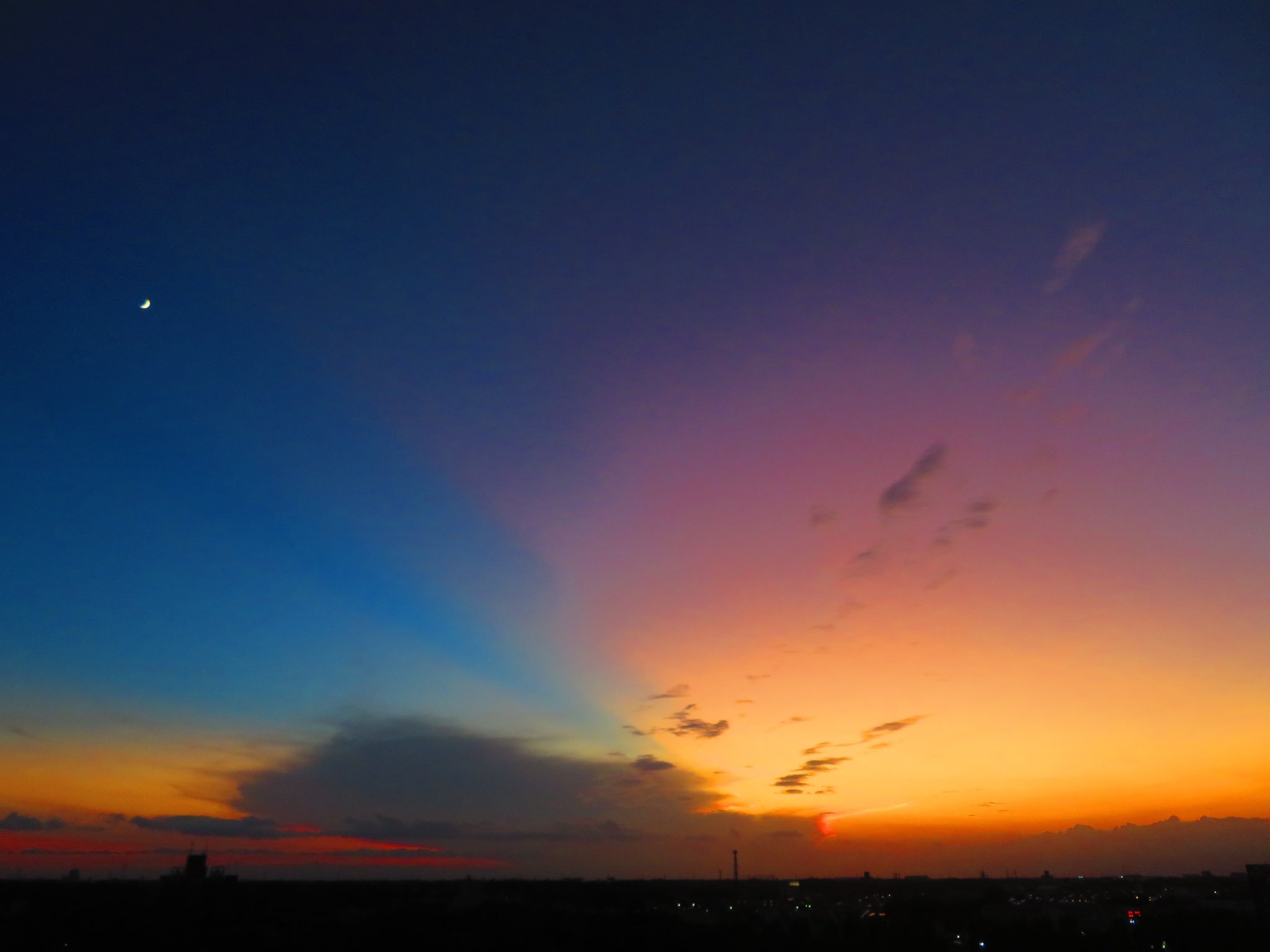 荒木健太郎 すごい夕焼け空に出会った 茨城県つくば市から西を向いて 富山県あたりで発達した積乱雲のかなとこ雲が焼け色に染まっています そこからのびる薄明光線に 雲の影の部分に佇む月 そして薄明の グラデーションに染まる空 夜へと向かう夕焼け