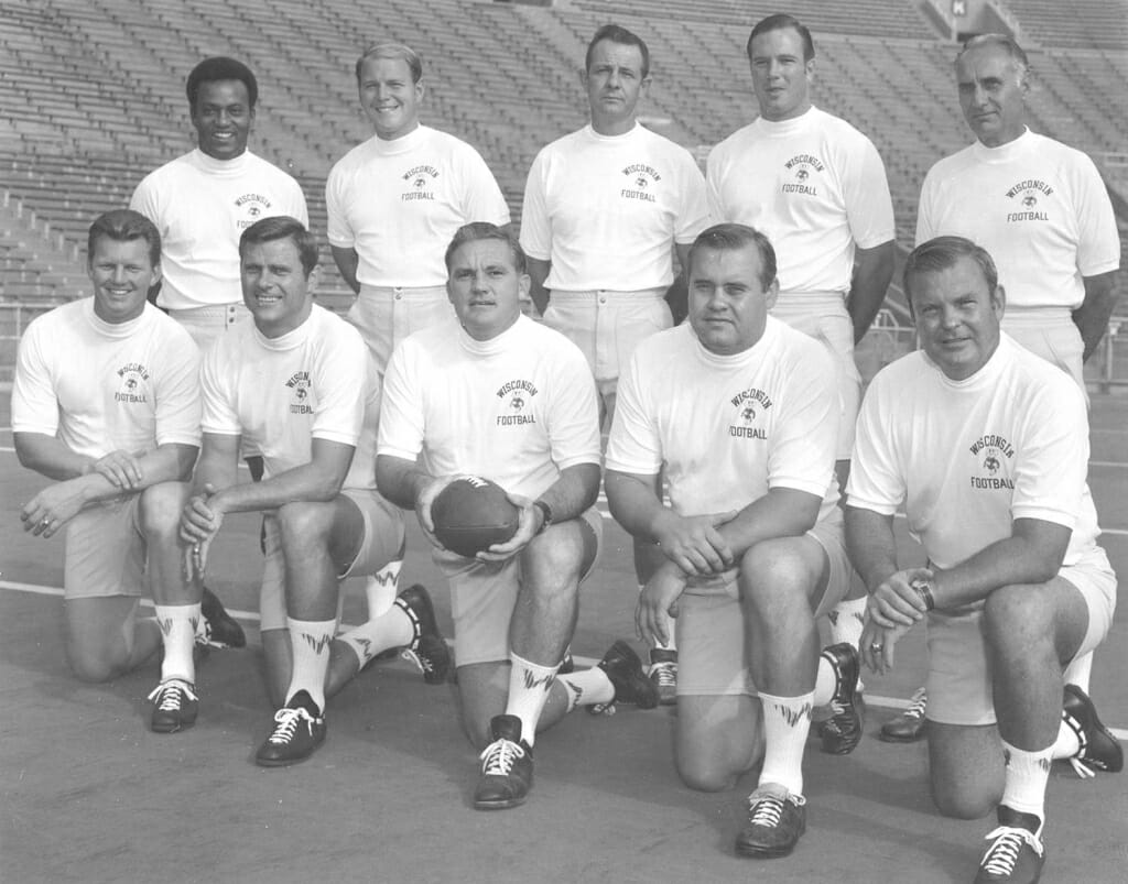 The 1970 Badgers football coaching staff, standing from left to right, Jim Martin, Stan Kemp, Paul Roach, Norm Dow, Vern Van Dyke. Kneeling: Chuck McBride, Bob Zeman, Head Coach John Jardine, Dick Teteak, Lew Stueck.