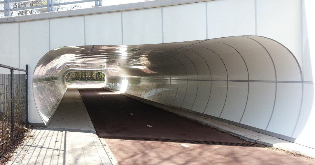 TTunnlar's tweet photo. Dagens peppbild är en #GC-tunnel i Nederländerna. Tidigare såg den ut som gång- och cykeltunnlar gör mest. Den var grå, rak och ganska trist. Visst har den blivit snyggare med ett kurvat #emaljsystem? #emaljinspiration #arkitektur #stadsutveckling #tunnel #uittenbosch #polyvision https://t.co/tv3yiEmtql