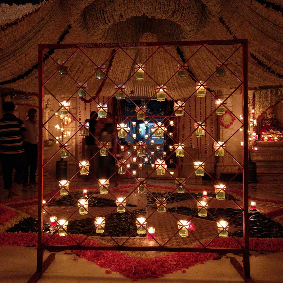 Pic from a Jain temple celebration I went to yesterday. Beautiful floral decoration - intricate and grand. Surreal due to the oil lamps. They don't use electricity inside the temple as much as possible to reduce their killing (bacterial life) footprint.  #surat  #jain