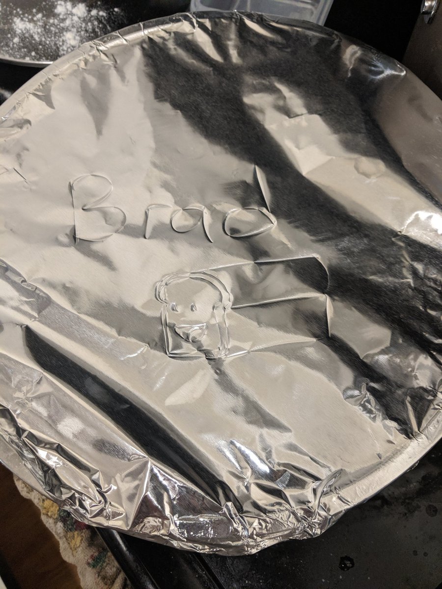 The dough covered in aluminum foil with Brad written on it and a picture of a smiling loaf of bread.