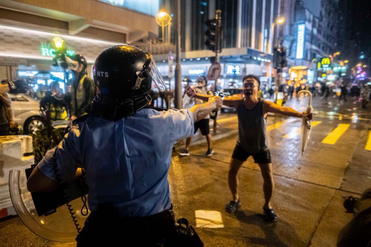 cng1238's tweet photo. An officer of the #HongKongPolice, after making the first gunshot in the anti-extradition movement, aiming his revolver at a civilian who begged the police not to shoot the protestors. The police later explained gun pointing was necessary because umbrellas are fatal weapons. https://t.co/fexk5cPlSK