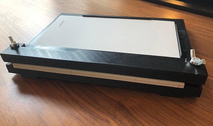 3D printed booking jig in black plastic, with a text block inside it.