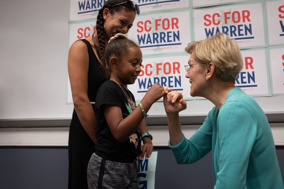 Elizabeth Warren does a pinkie promise with a young girl.