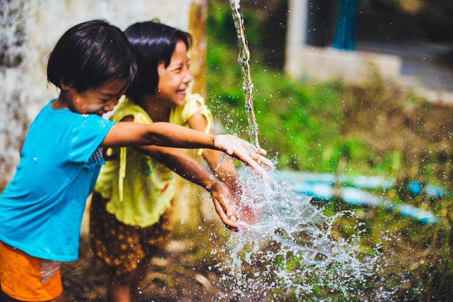 children playing in a water foundation, smiling