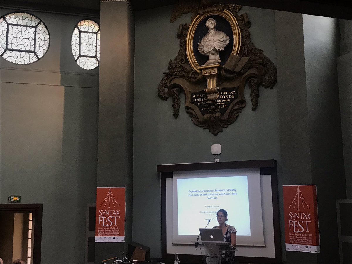 cigilt's tweet image. Ophélie LaCroix discusses her work on dependency parsing as sequence labelling at #SyntaxFest2019 in the beautiful amphitheatre at the Grand Amphitheatre du monde anglophone 
of the Sorbonne, Paris