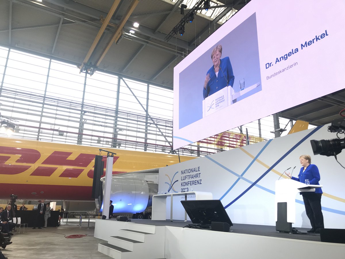 DeutschePostDHL's tweet photo. Hoher Besuch in unserem #DHL Hangar. Kanzlerin #Merkel betont, Leipzig habe damals in besonderer Weise für den Standort geworben. Mit Mut und Leistung sei hier etwas Neues geschaffen worden und die 1. Nationale #Luftfahrtkonferenz finde deswegen zu Recht in #Leipzig statt. https://t.co/3ZthVGbKp0