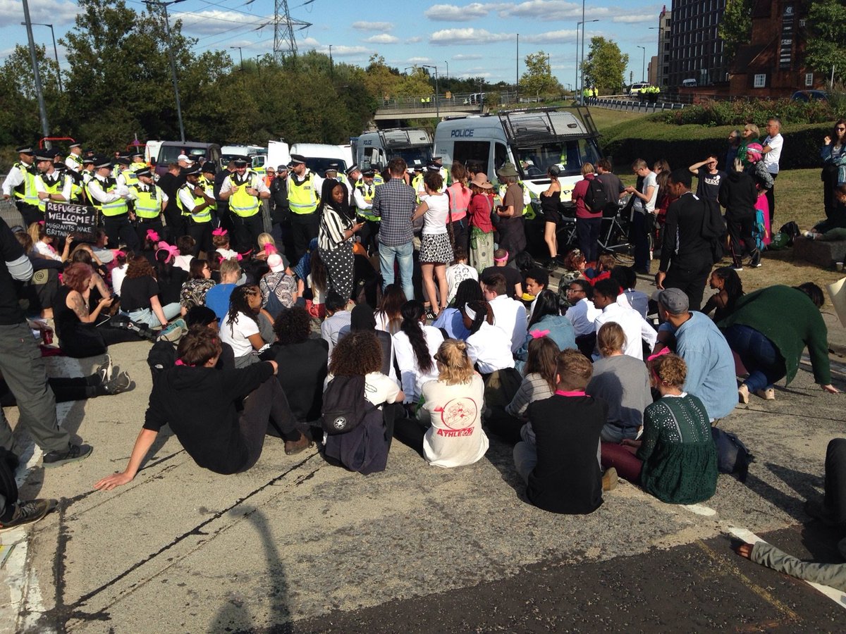 CAATuk's tweet photo. Sit in the road as police cutting team tries to remove a lock-on blocking the road to the DSEI arms fair #StopDSEI #freemovementforpeoplenotarms https://t.co/lCb2pjzC6m