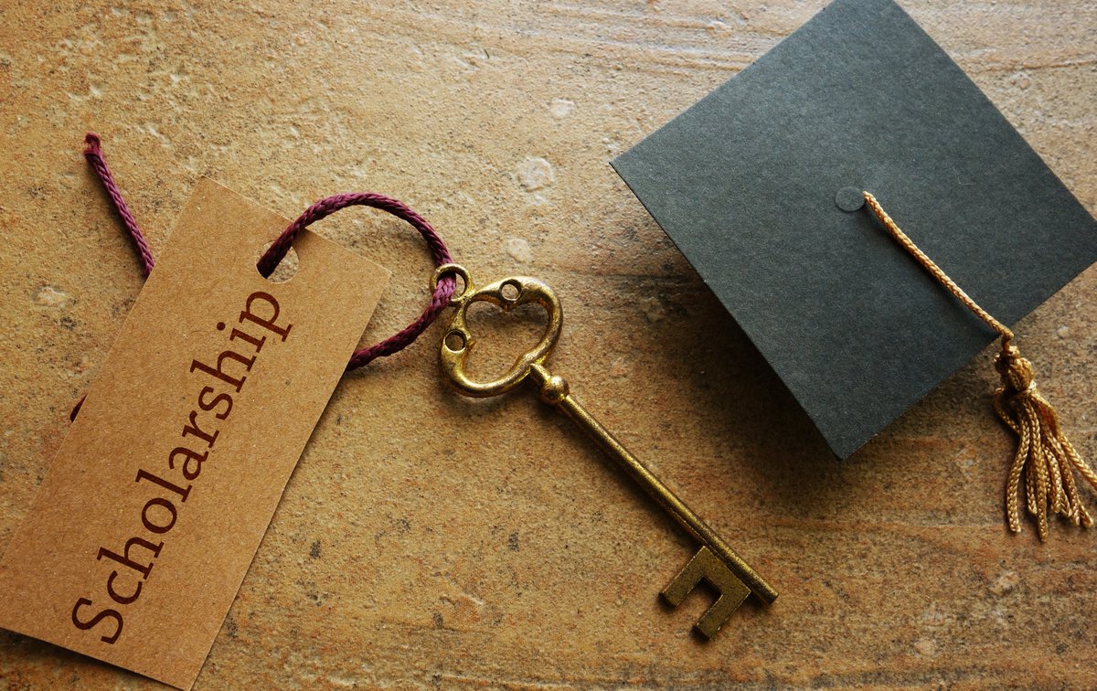 A scholar hat and a key with a label attached with the word Scholarship on it