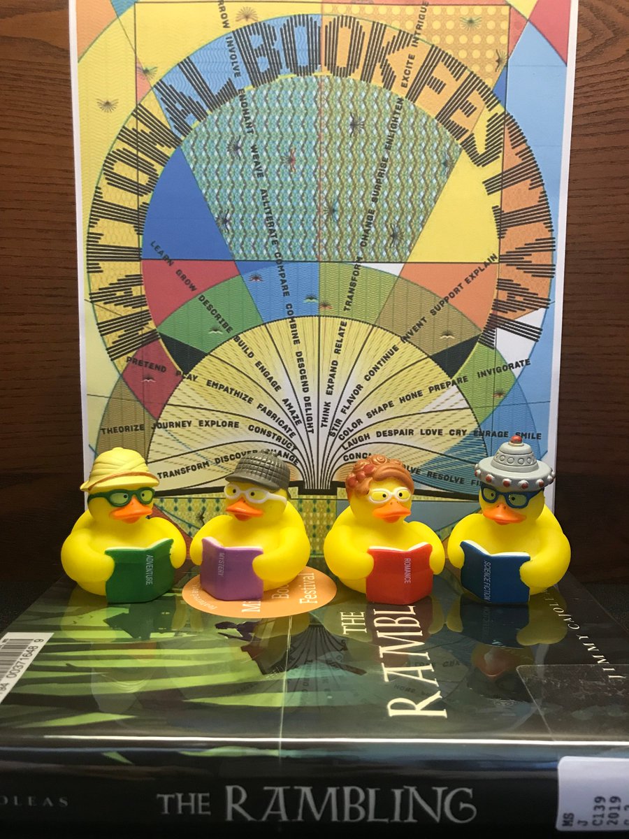 Four rubber ducks wearing hats and glasses are holding books. They sit atop the book The Rambling by Jimmy Cajoleas and are posed in front of the 2019 National Book Festival Poster.