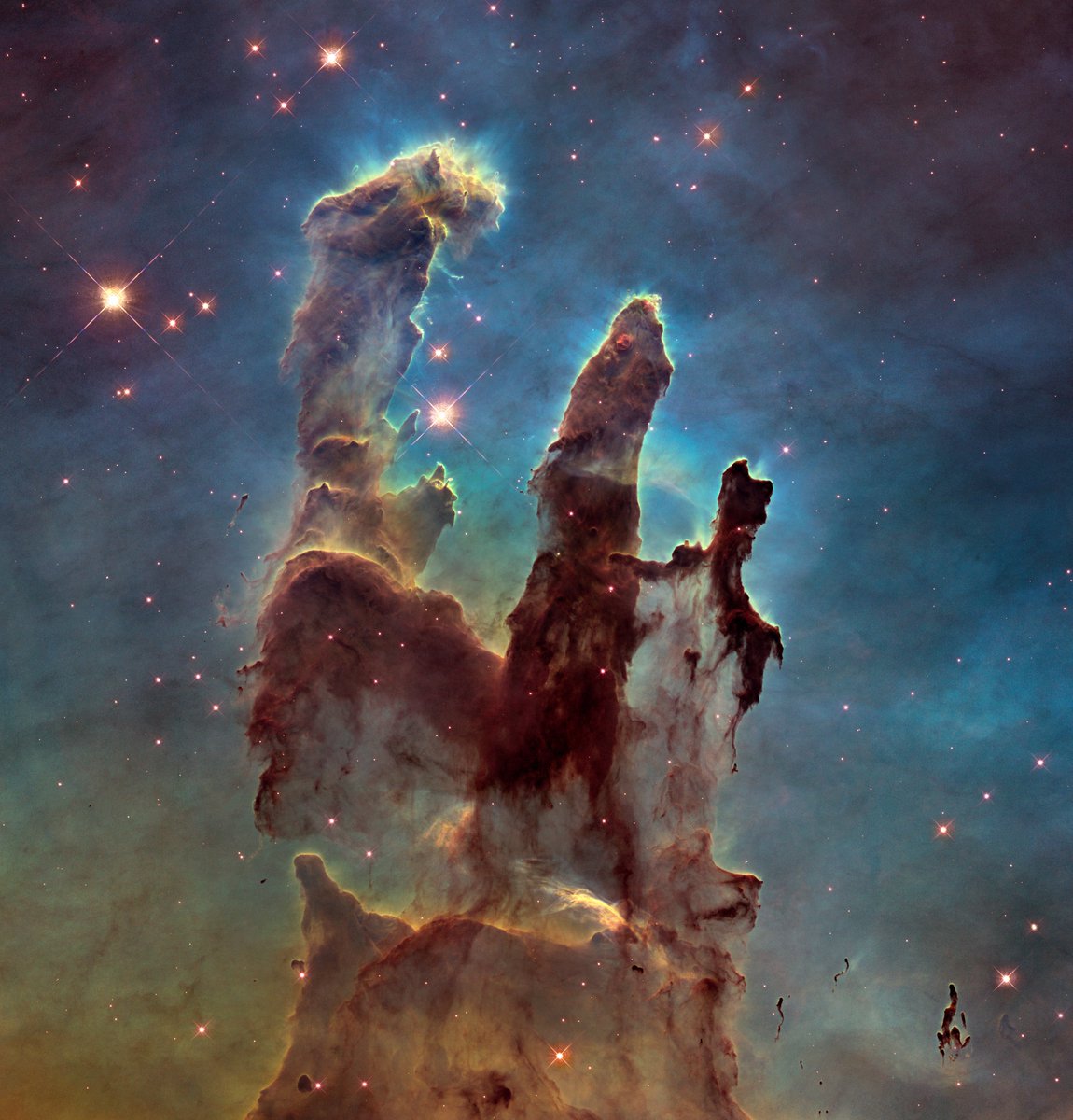 An image of a nebula called "Pillars of Creation." It's a few columns of dust and gas that appear to be back-lit. There are also a couple of stars in the picture with four-pointed spikes coming off them.