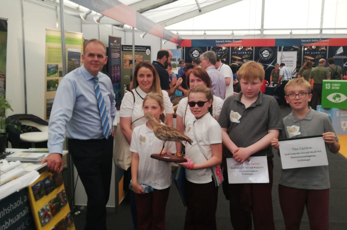 DeptCEE's tweet photo. Some very special visitors from @moyle_n National School in Newtowncunningham in Donegal showing Minister @McHughJoeTD their school project on the decline of the curlew. These beautiful tiles will be displayed at Inch Island Wildfowl Reserve #GovVillage #Ploughing19 https://t.co/M7weRBgIZr
