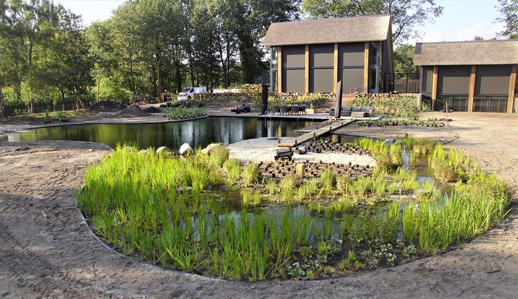 VOH_Appeltern's tweet photo. De aanleg van deze natuurlijke tuin met zwemvijver in Vught vordert gestaag. De zwemvijver is inmiddels klaar. Het moeras- of helofytenfilter is ingeplant. De zandstrandjes en de vlonder van eikenhout nodigen uit om aan de waterkant te relaxen. Een zeer verleidelijk vooruitzicht! https://t.co/u7HxabaXNv
