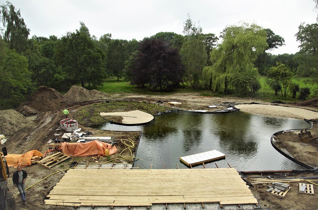VOH_Appeltern's tweet photo. De aanleg van deze natuurlijke tuin met zwemvijver in Vught vordert gestaag. De zwemvijver is inmiddels klaar. Het moeras- of helofytenfilter is ingeplant. De zandstrandjes en de vlonder van eikenhout nodigen uit om aan de waterkant te relaxen. Een zeer verleidelijk vooruitzicht! https://t.co/u7HxabaXNv