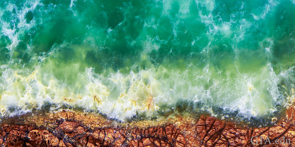 GIAnews's tweet photo. This green #opal from Tanzania, colored by nickel, contains fragments of matrix trapped within the stone. The opal resembles an aerial view of a coastline. Purchase the new Micro-Features of opal chart. https://t.co/zjUGQztsIk https://t.co/XGZTEzrH0f