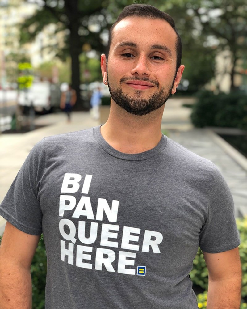 Person wearing grey t-shirt that reads bi pan queer here