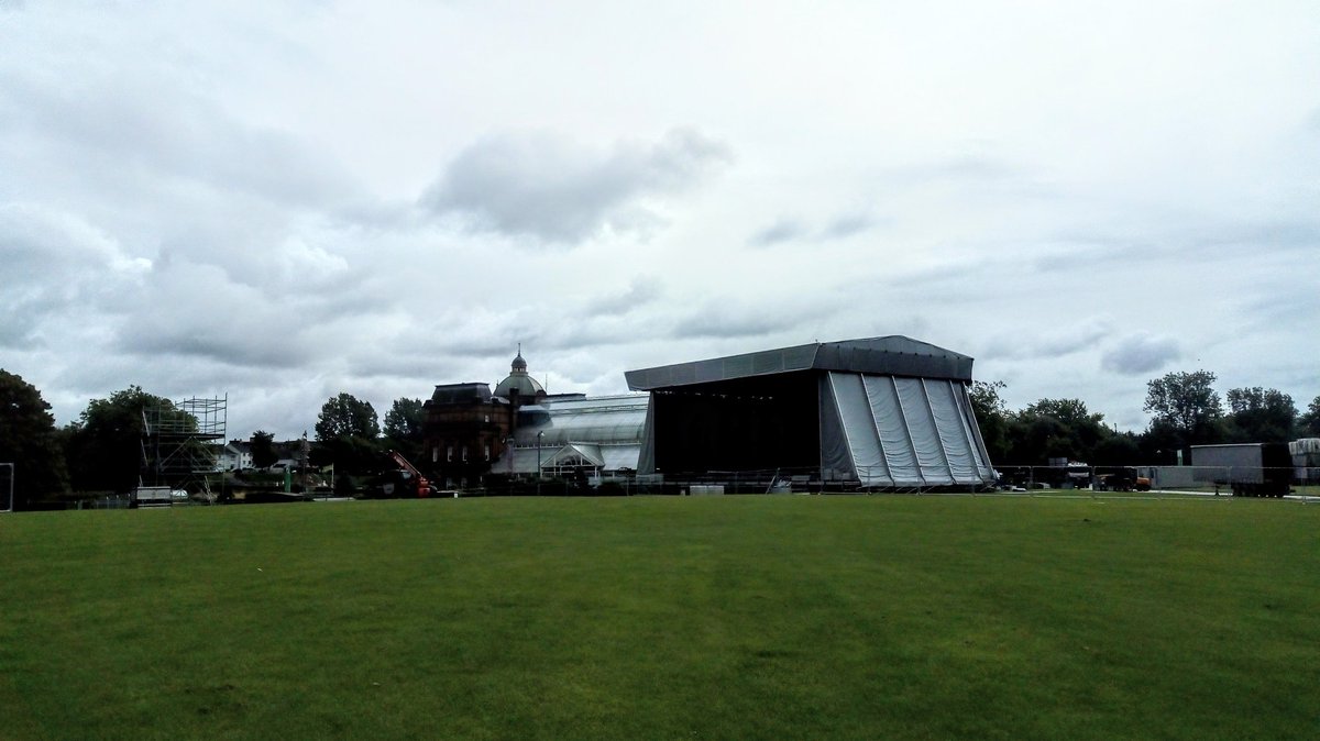 SaveTWG's tweet photo. When will the Winter Gardens at Glasgow Green reopen? Dwarfed today by building of The Proms stage. 9th month of closure, no repairs done, overgrown weeds of vegetation, signs of neglect? Answers please! #SaveTWG https://t.co/PMaYBhRrpx