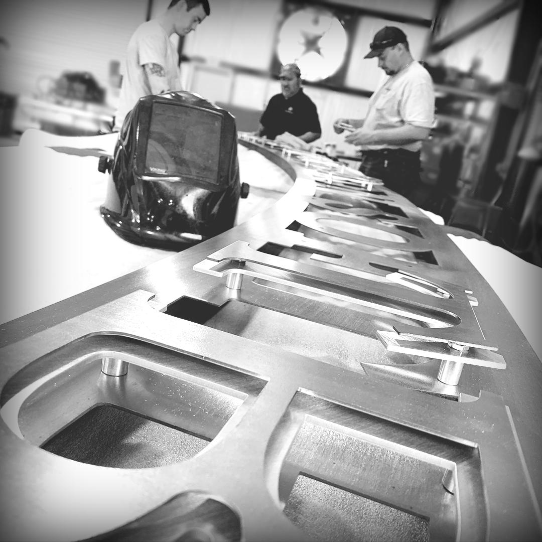 AlabamaMetalArt's tweet photo. Ben, Joe, and Logan preassemble an intricate arched entrance sign. #signshoplife #customsigns #businesssigns #signcompany #outdoorsigns #signstore #signdesign #customsignage #signfabrication #signmaking #fabrication https://t.co/sntwCyMCru
