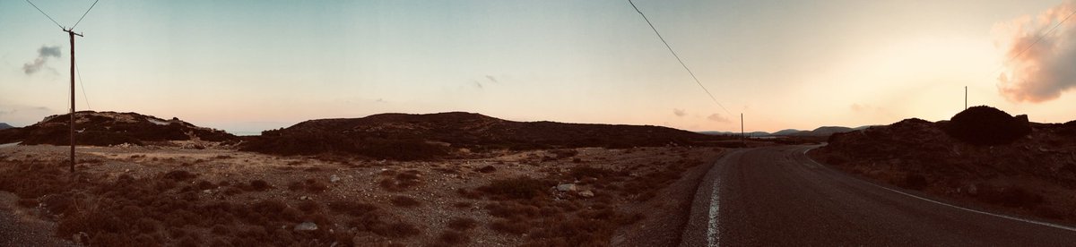 A road cuts through a desertified landscape at sunset