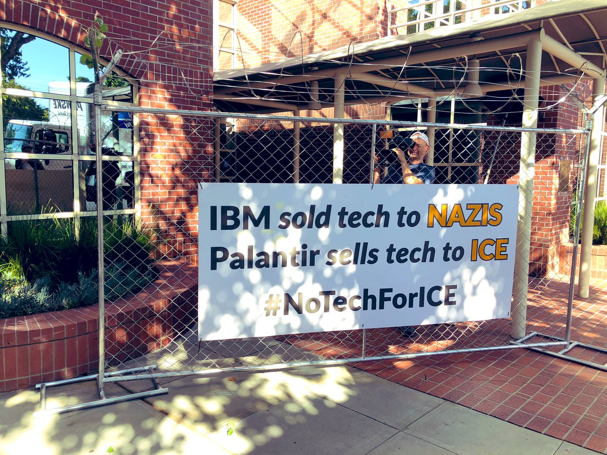Banner & barbed wire blocking entrance to Palantir ‪IBM sold tech to Nazis Palanti‬ seldom tech to ICE