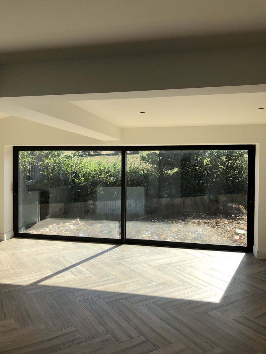 Just look at that view 😍 Here we have installed a 5m 2 pane lift and glide Reynears aluminium sliding patio door with 67mm slim interlock, The doors are finished in Ral 8005m black cotex finish and complement the herringbone floor for that all important rustic look ❤️